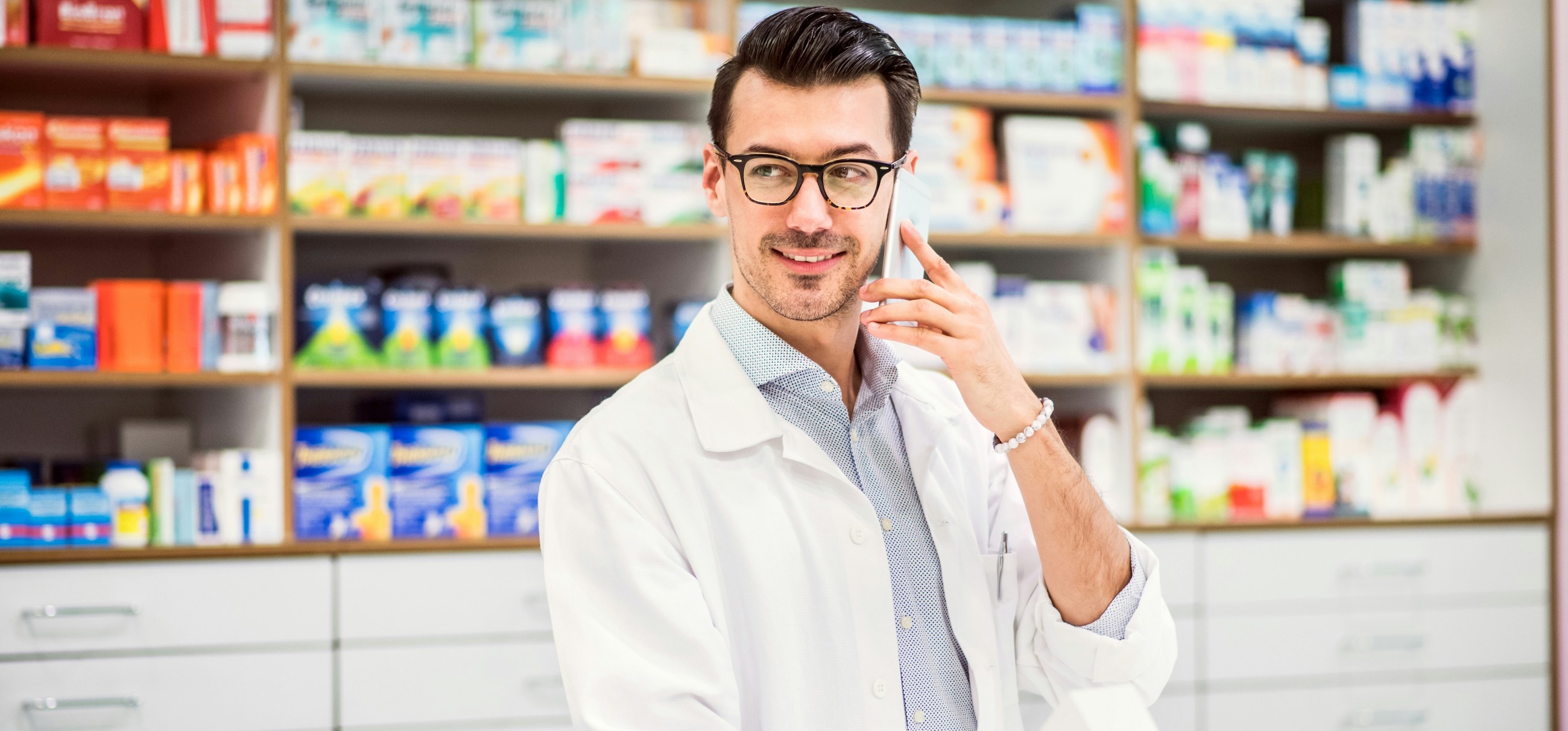A pharmacist takes a phone call behind the pharmacy counter