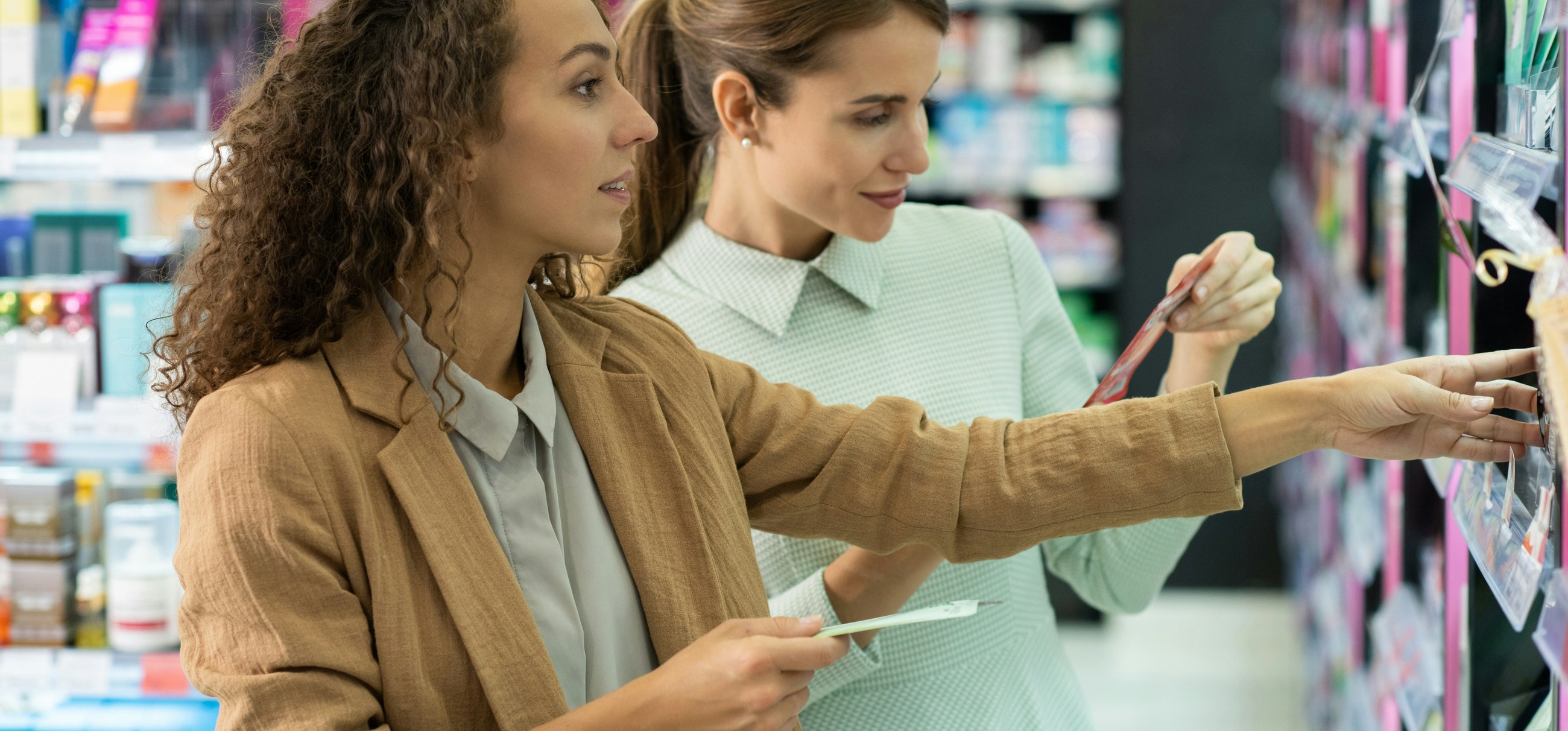 Two women compare products on a drugstore shelf
