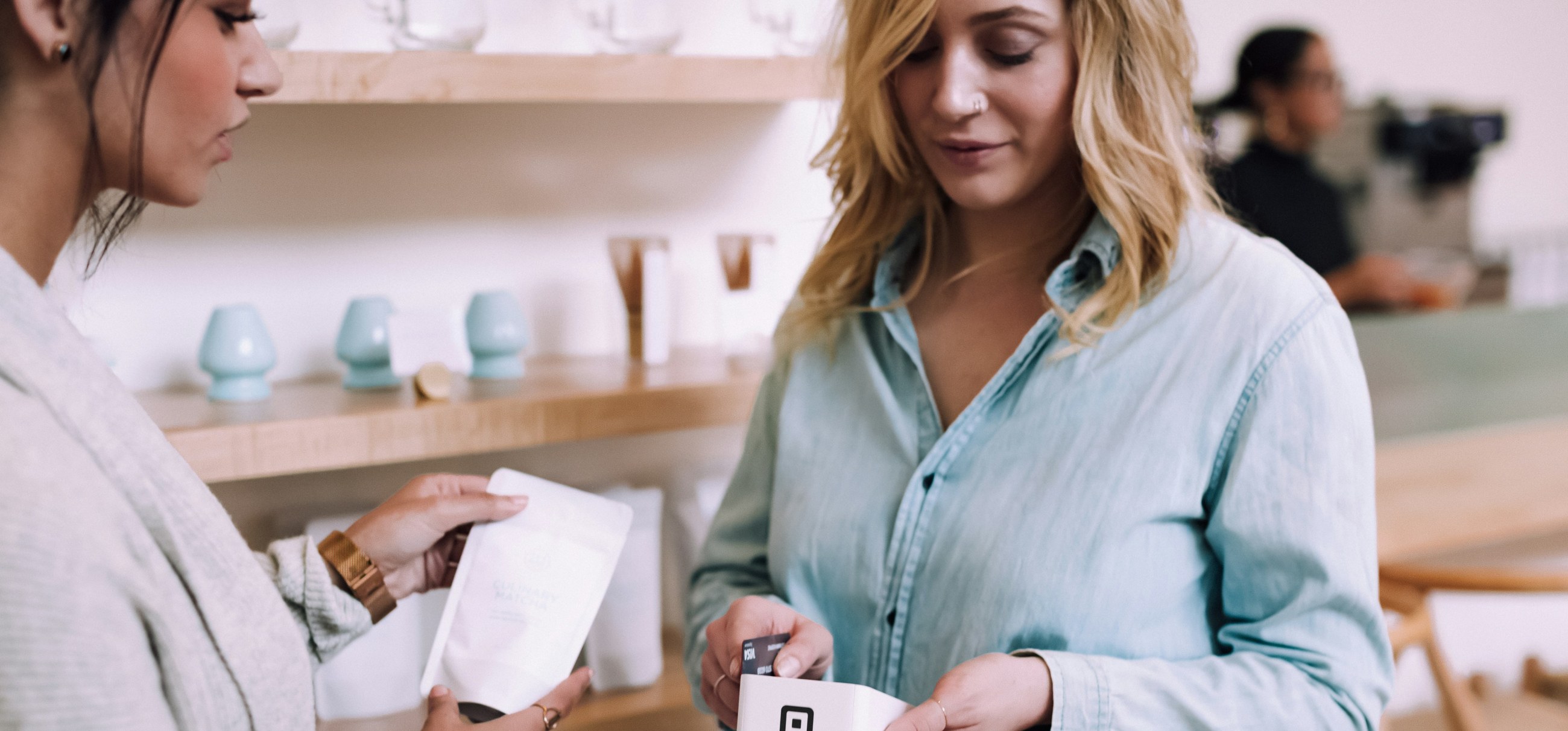 A customer pays by card at a shop counter