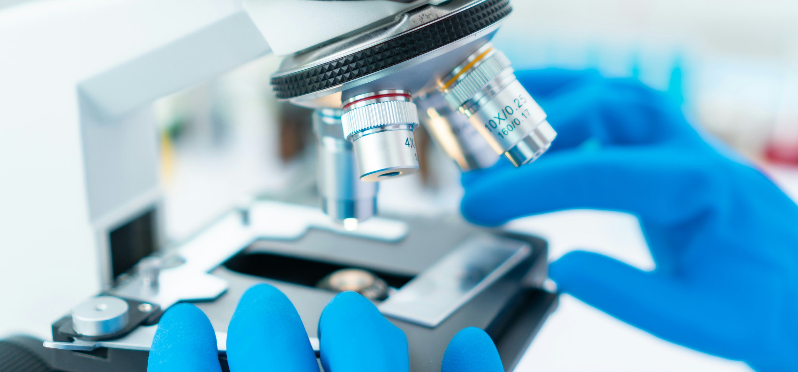 A laboratory technician adjusting the objective lenses on a microscope