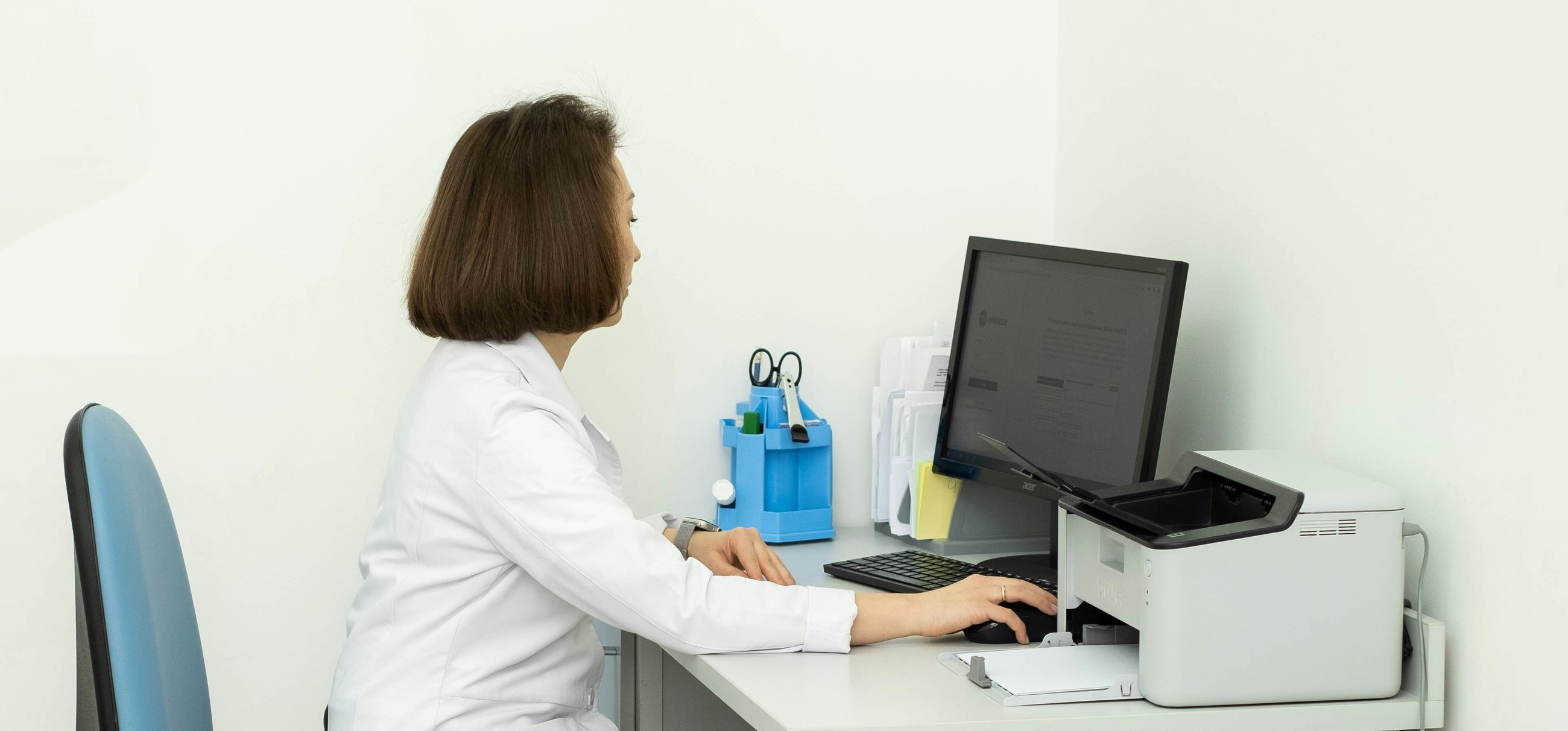 A laboratory doctor at a desk reading a record on a computer screen