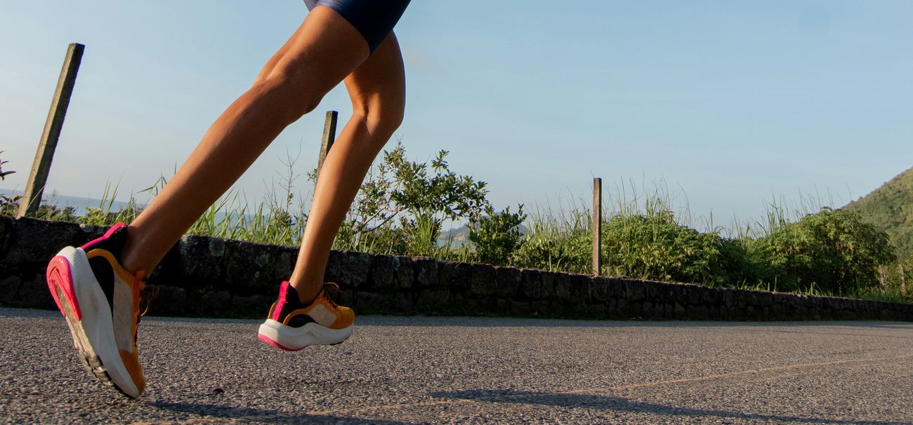 A runner mid-stride on a coastal road in the morning sun