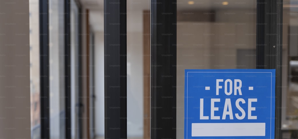 A lease sign hanging on the glass door of an empty unit