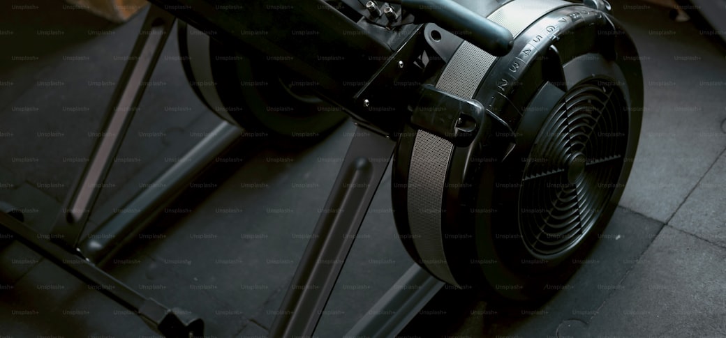 A rowing machine with a fan flywheel on a dark gym floor