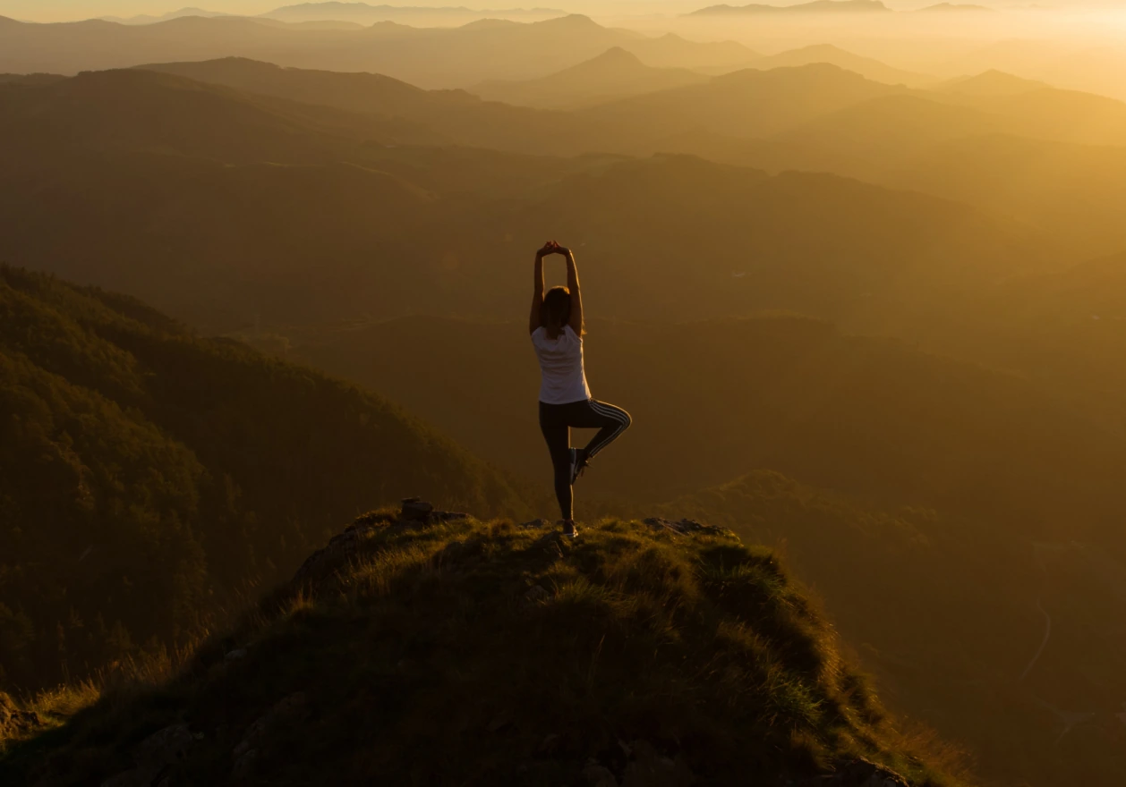 person doing yoga on top of a mountain with sunset view