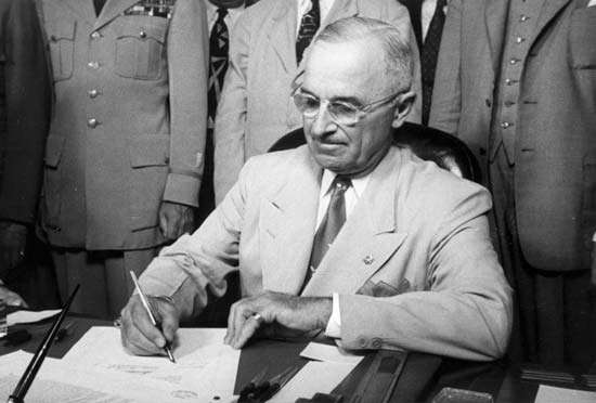 President Truman signing refugee legislation at his desk