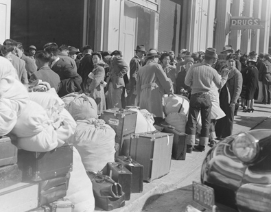 Japanese Americans with luggage awaiting forced evacuation to internment camps (National Archives)