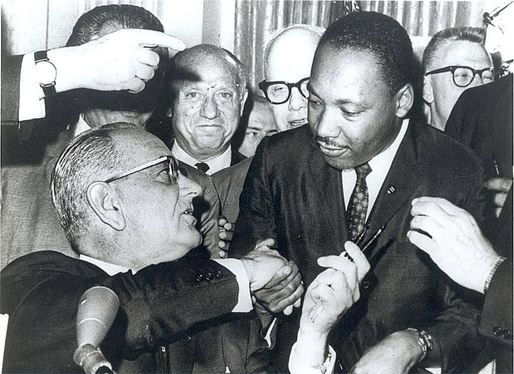 President Lyndon B. Johnson signing the Civil Rights Act with Martin Luther King Jr. and others present