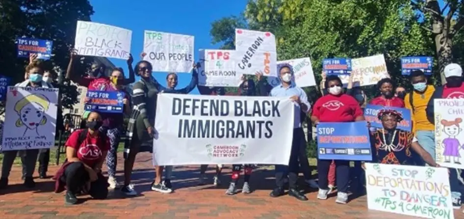 Rally for Black immigrant deportation defense with signs and speakers