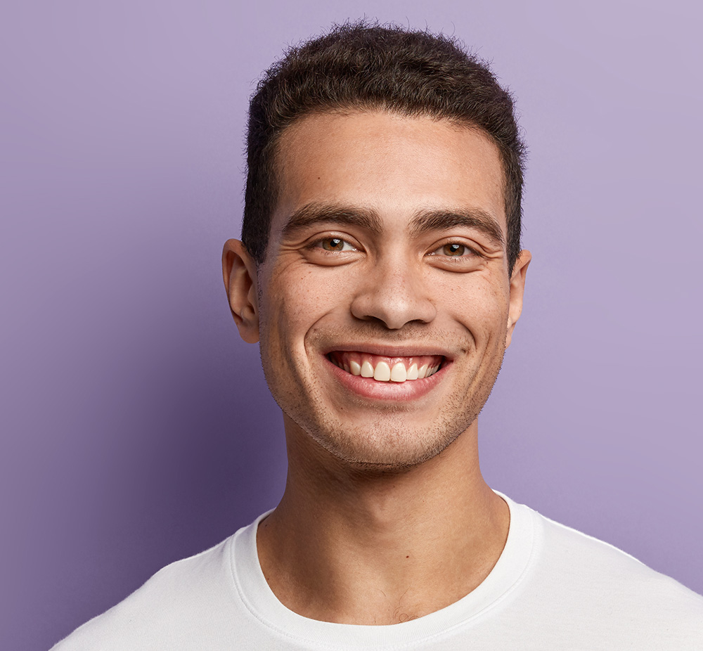 Smiling person in white shirt against purple background