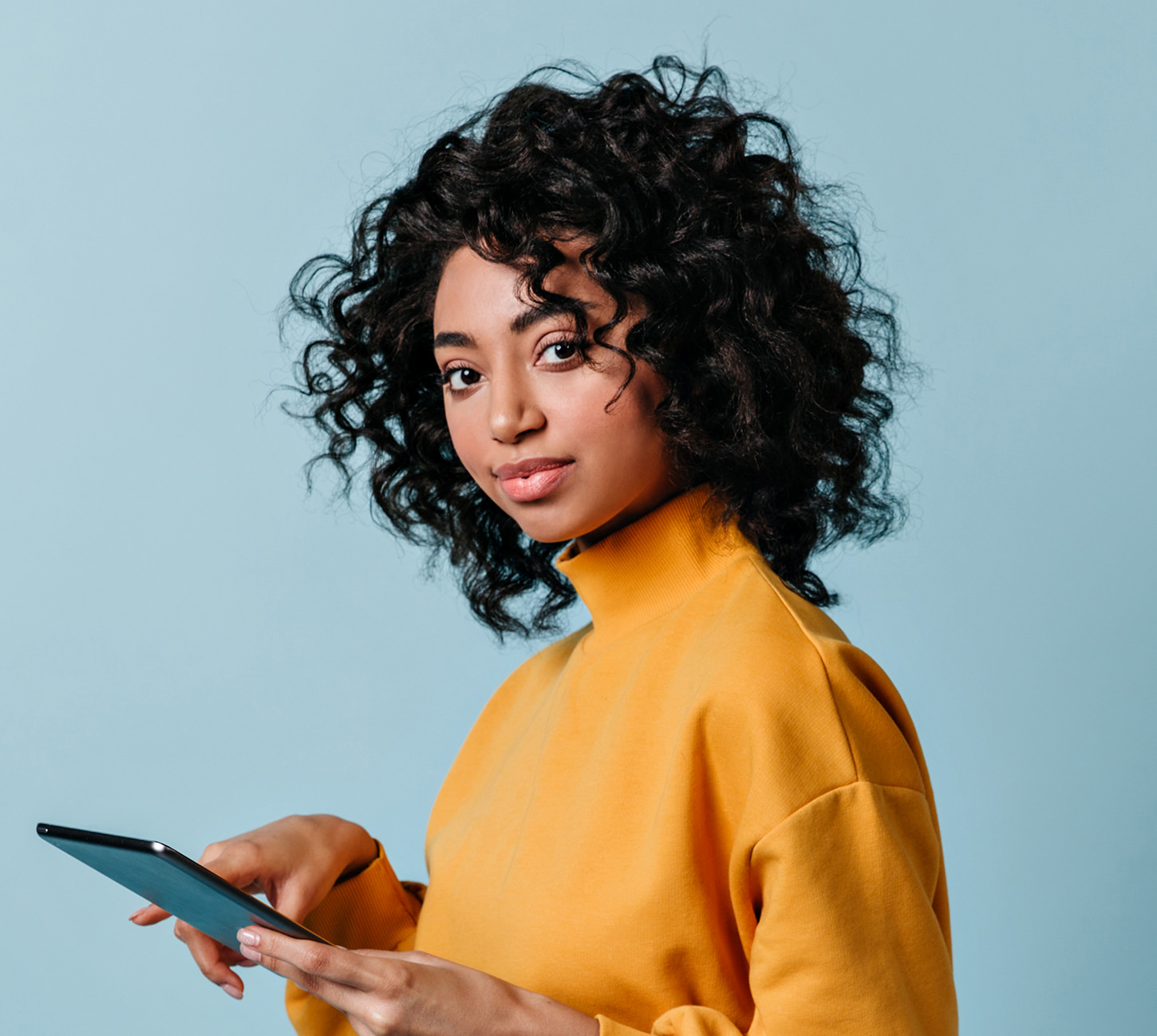 Woman in yellow sweater using tablet against blue background