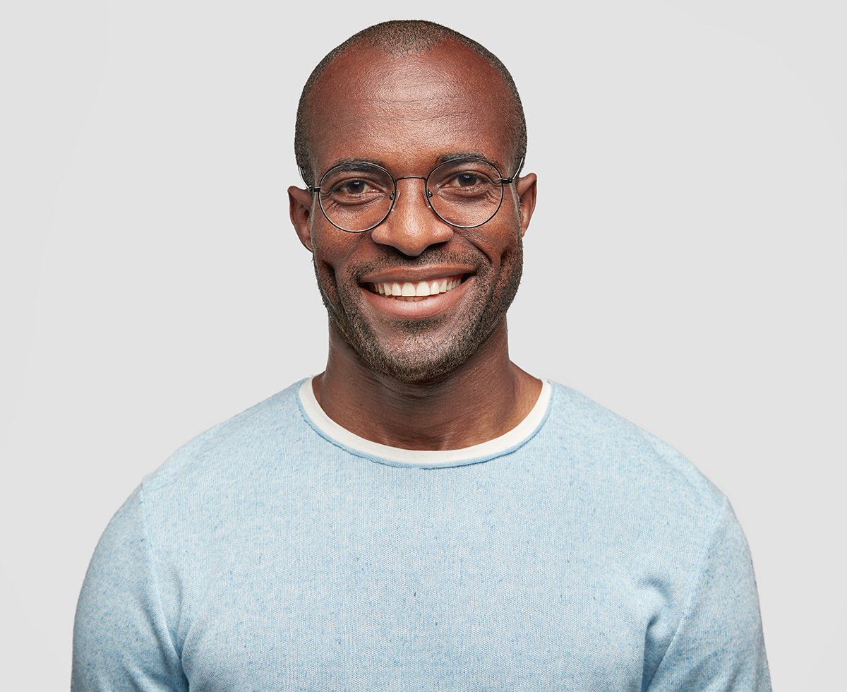 Smiling man with glasses wearing blue sweater on light background