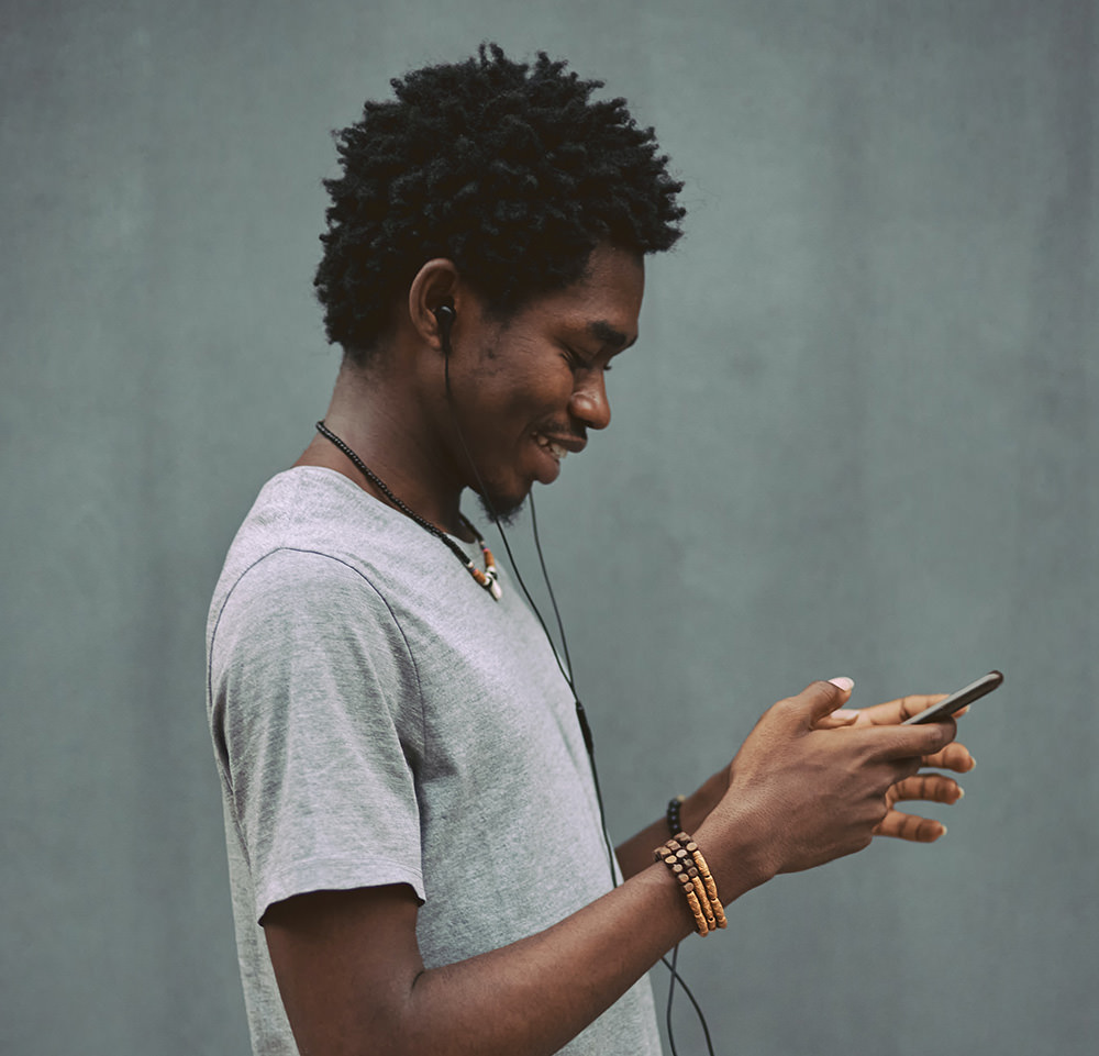 Person with earbuds smiling while looking at smartphone