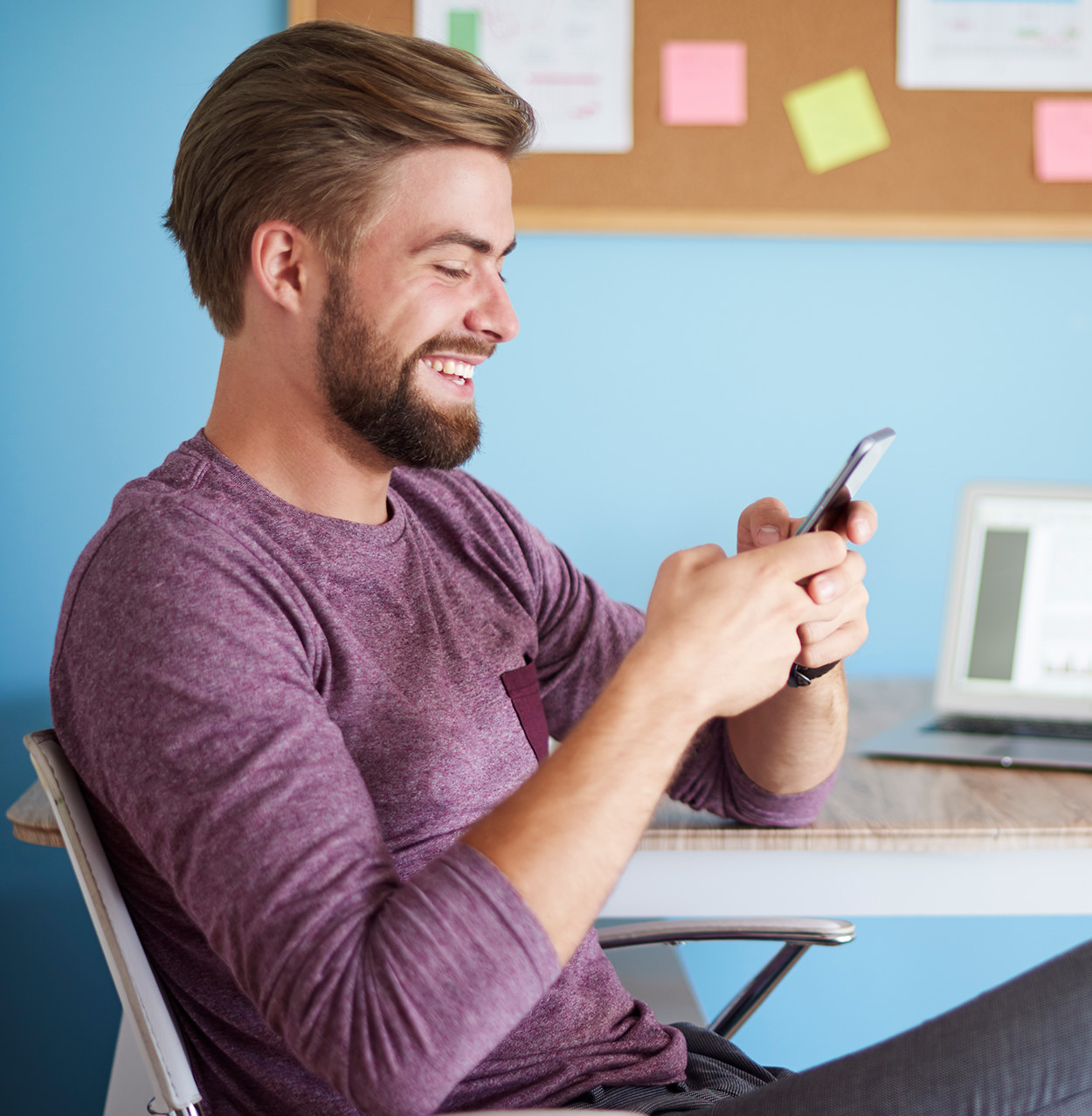 Smiling person using smartphone at desk with colorful sticky notes
