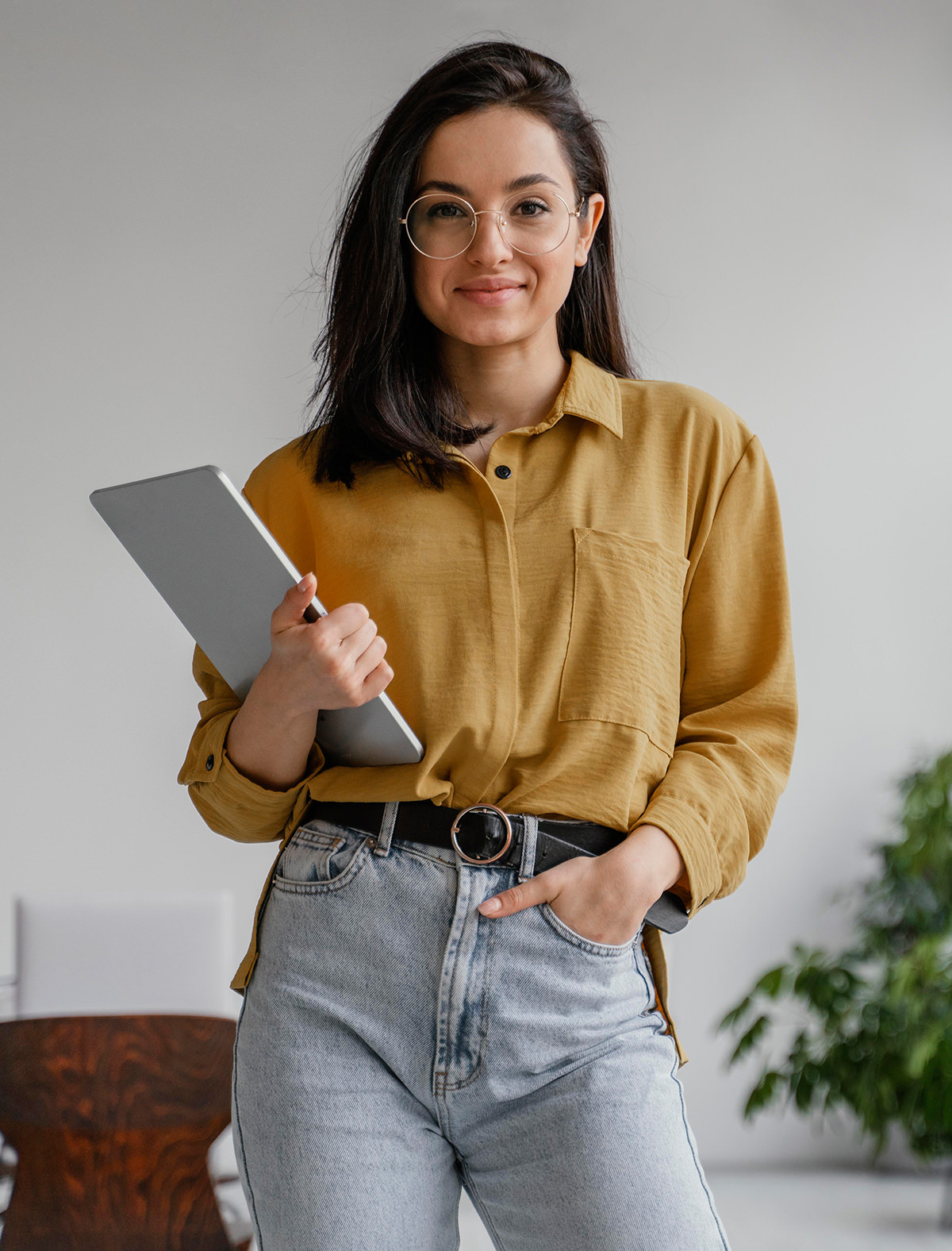 Professional woman in yellow shirt holding tablet, smiling with glasses