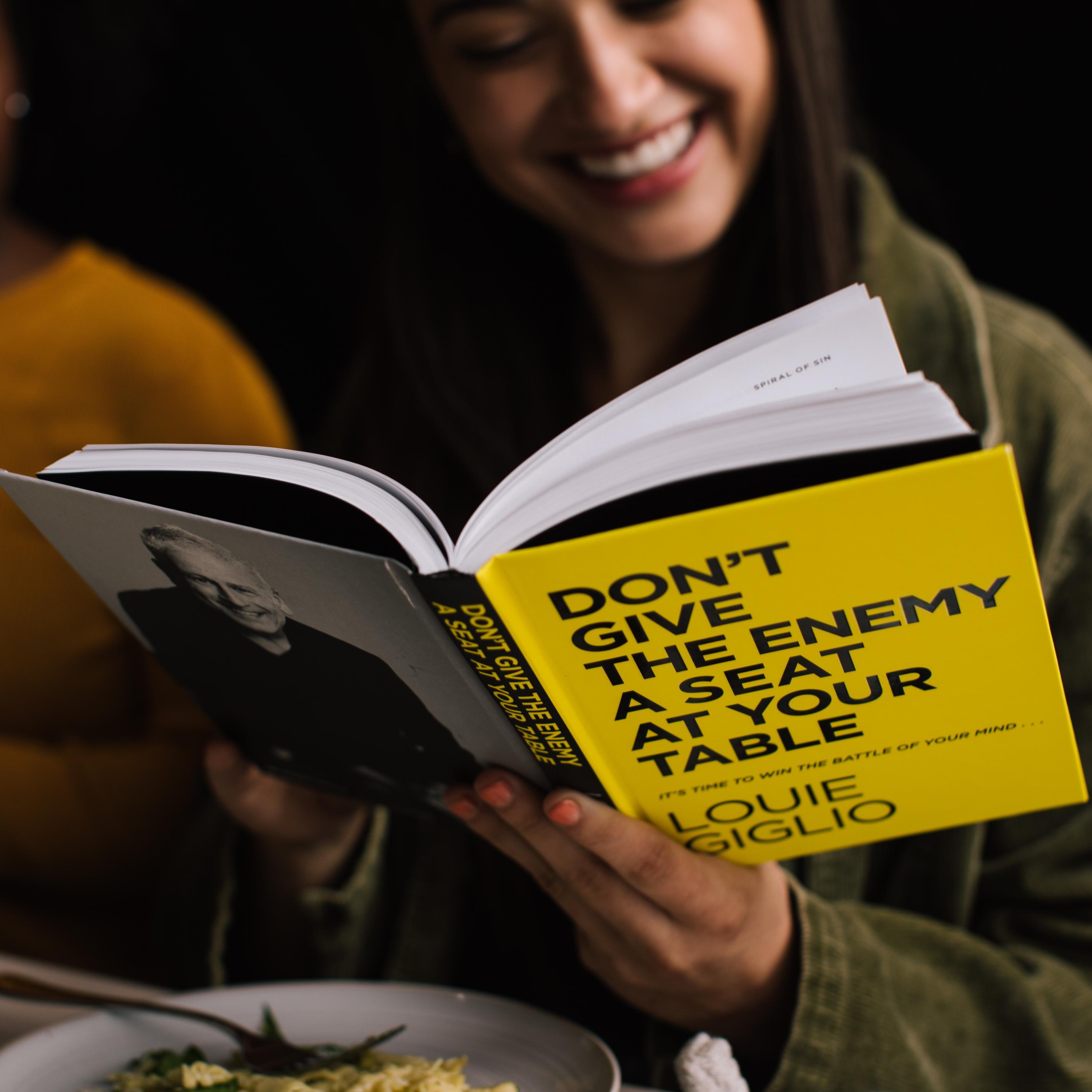 Woman reading Don't Give the Enemy a Seat at Your Table