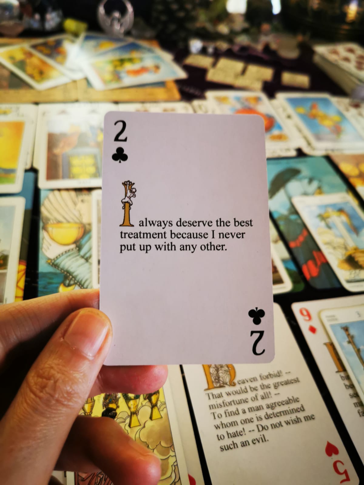 Layered tarot spread using various decks and the Two of Wands poker card with affirmation: 'I always deserve the best treatment.'