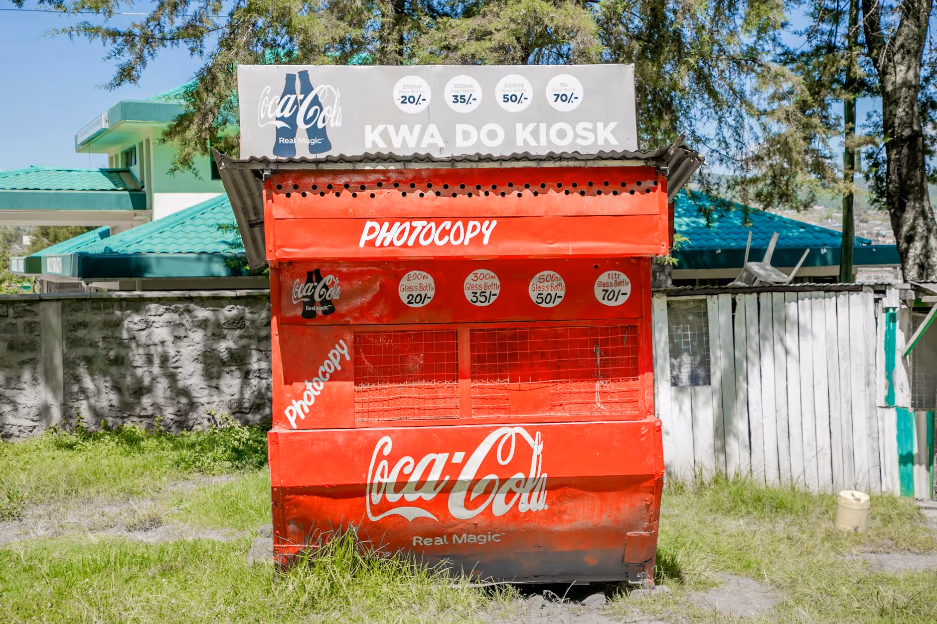 Bright Coca-Cola kiosk in a sunny Kenyan town, featuring distinct red branding.
