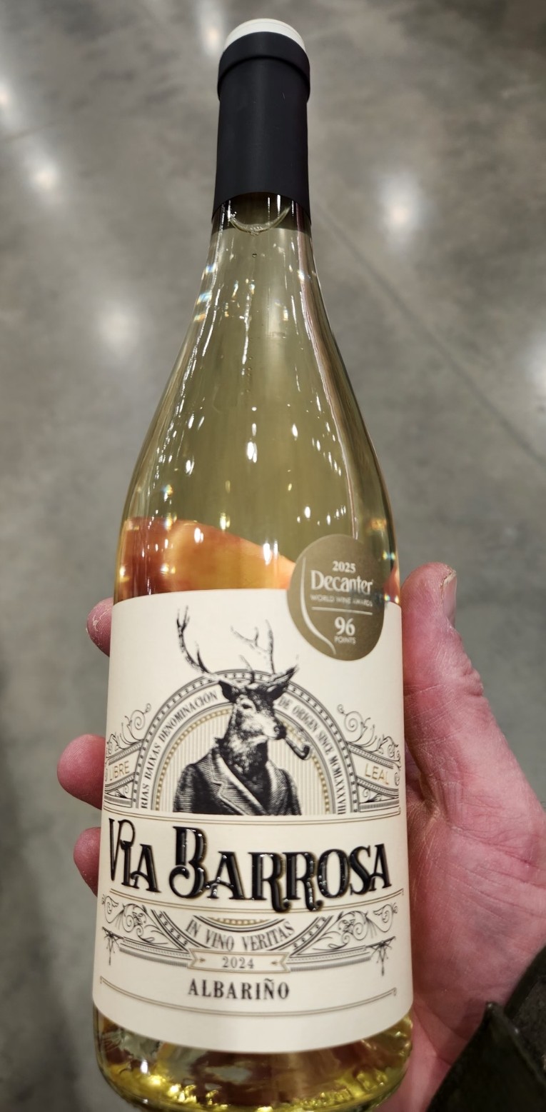  holding a bottle of Via Barrosa Albariño 2024 with Decanter 96-point award sticker.