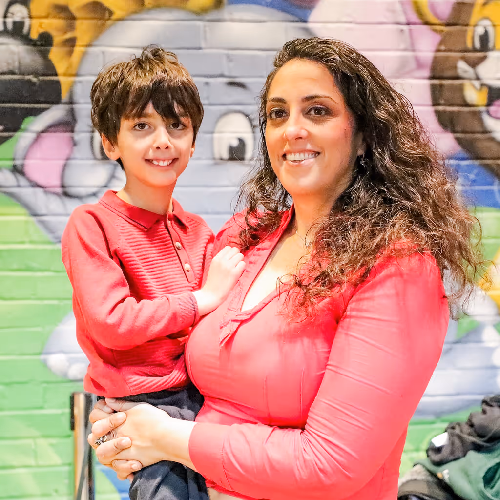 Mother and son smiling together in front of colorful graffiti wall