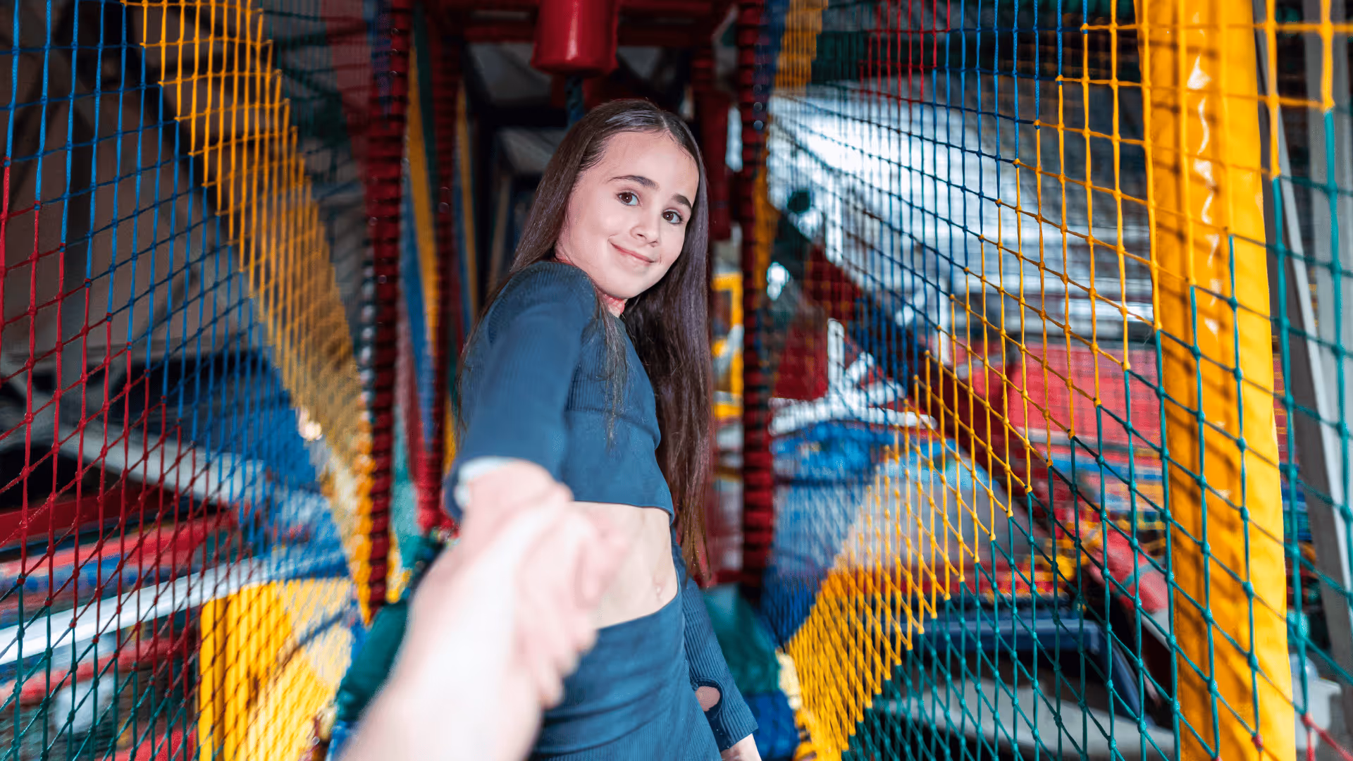 Child smiling inside colorful netted playground structure