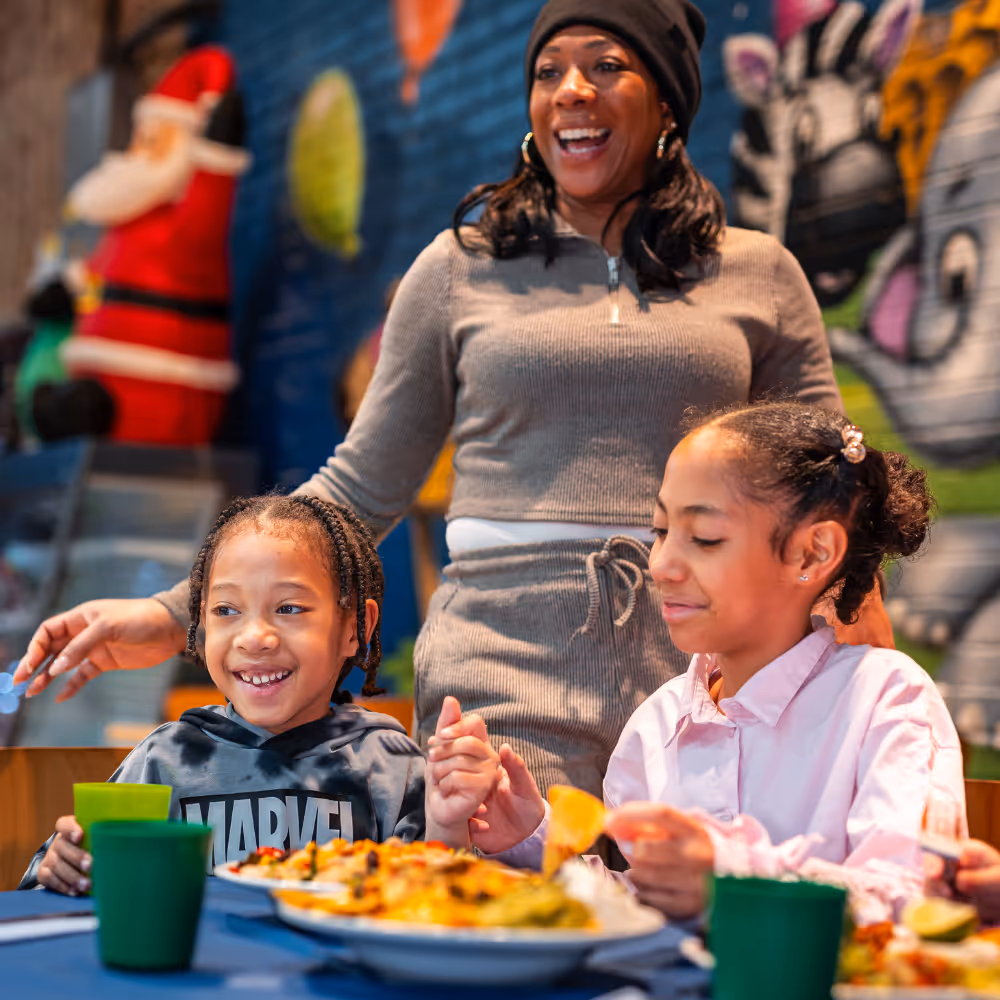 Mother and two daughters enjoy meal together with colorful graffiti background