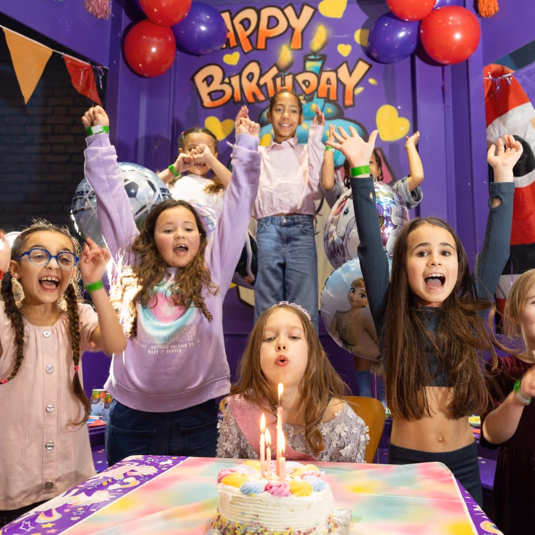 Excited girls celebrating birthday with cake, balloons, and candles