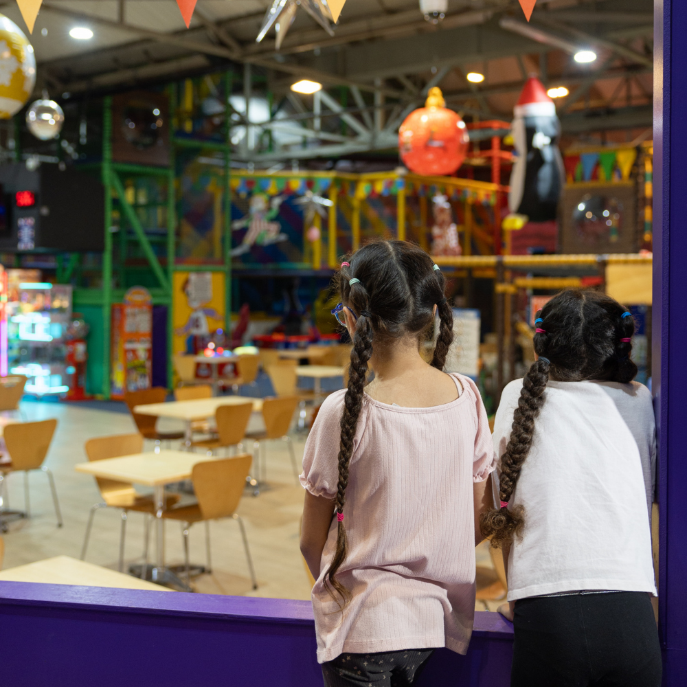 Girls looking out over a huge soft play arena from a party tent during a birthday party