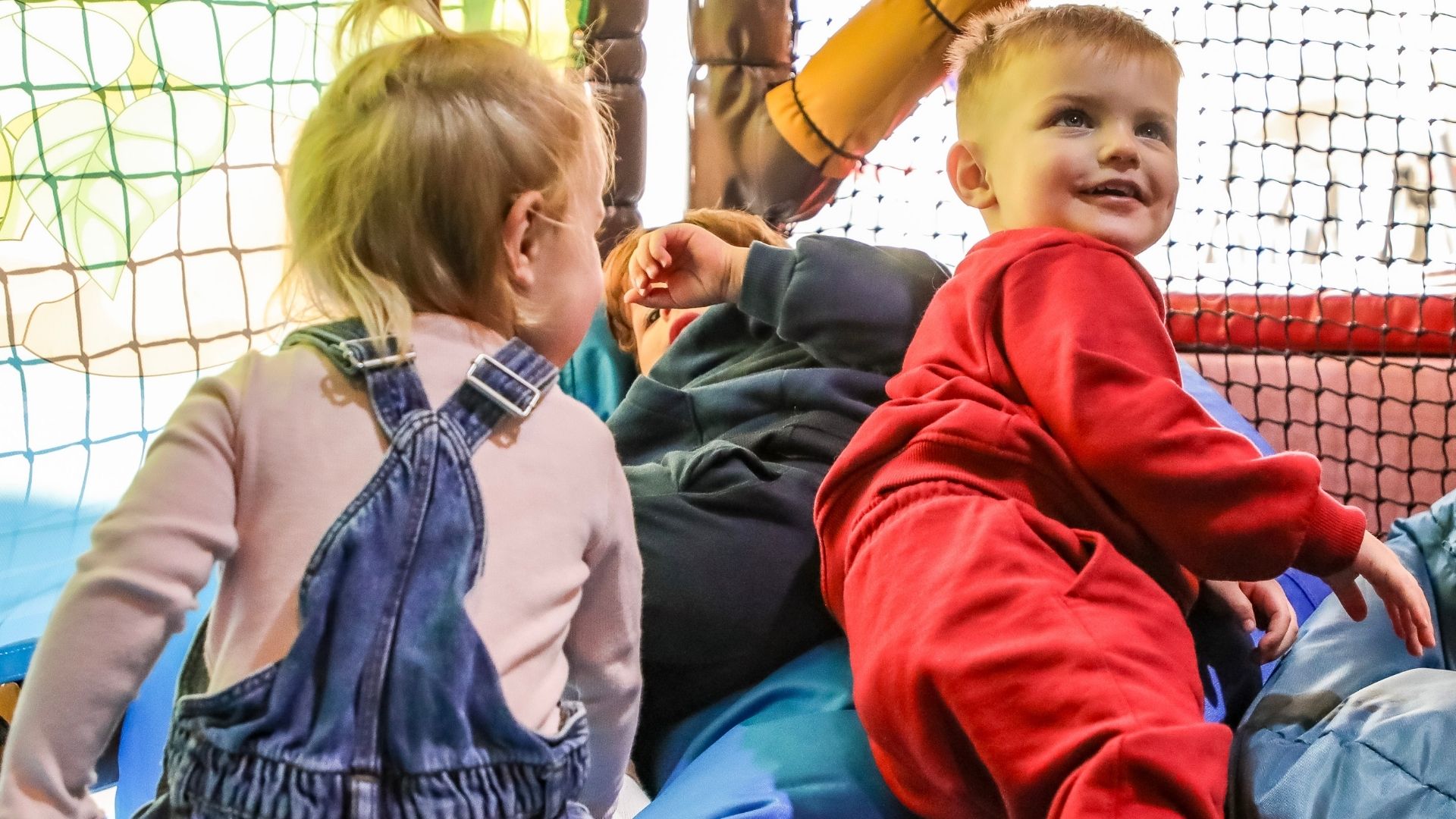 Young children playing together on a soft play frame 