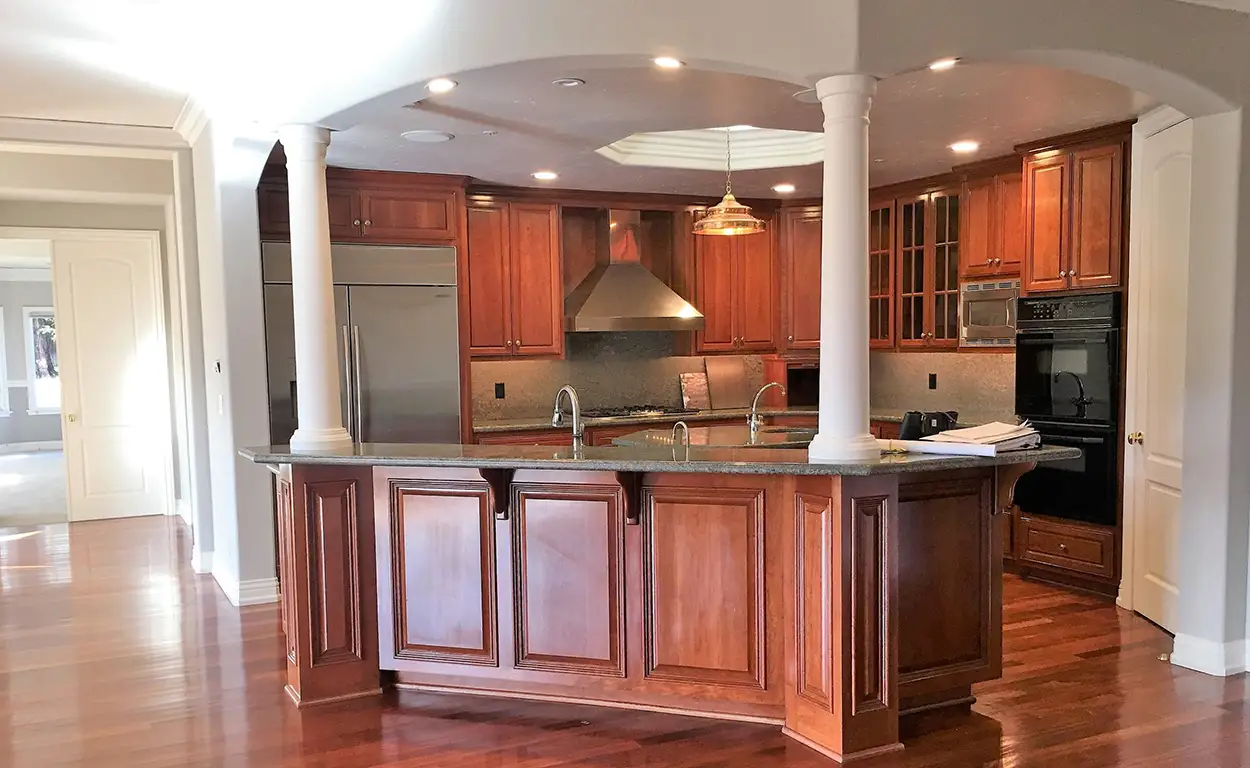 Classic kitchen renovation in Denver with cherry wood cabinets, double island sink, and architectural columns for an elegant, timeless layout.