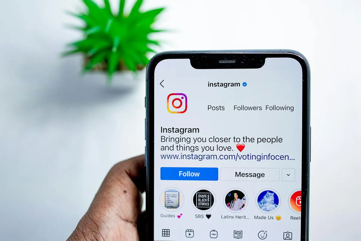 A person is holding a smartphone and browsing instagram.