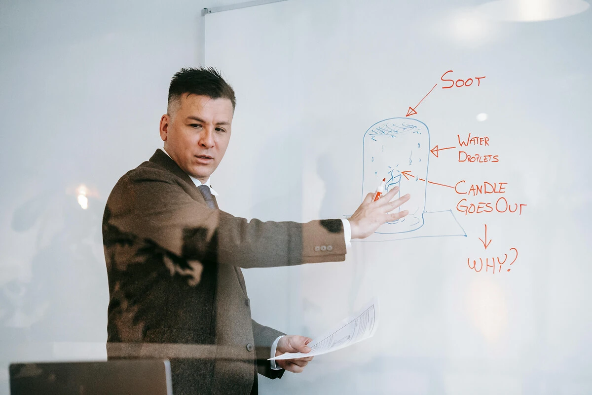 An online tutor writes on a whiteboard, instructing students during an online class session.
