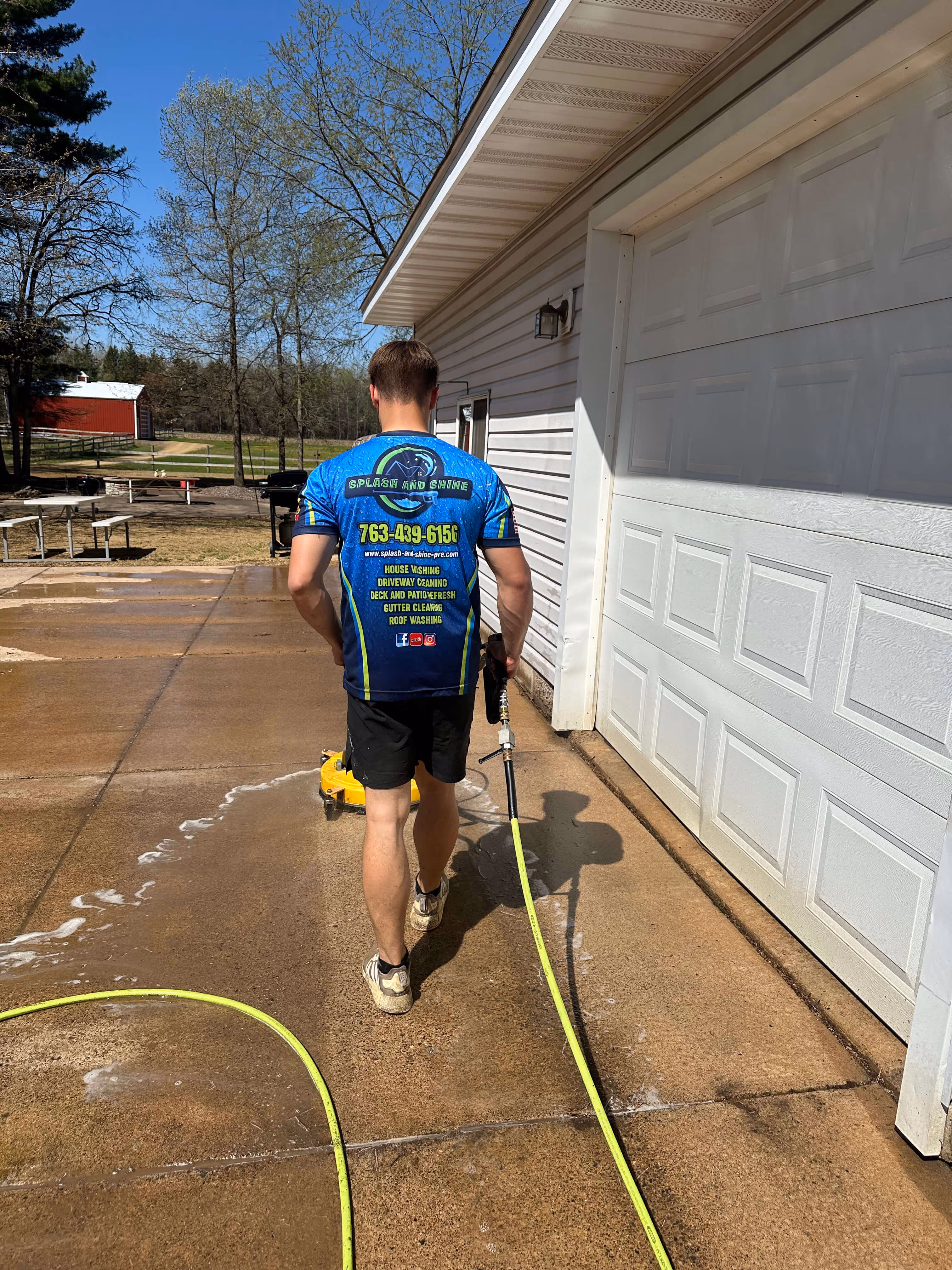 Splash & Shine crew pressure washing a concrete driveway with a surface cleaner