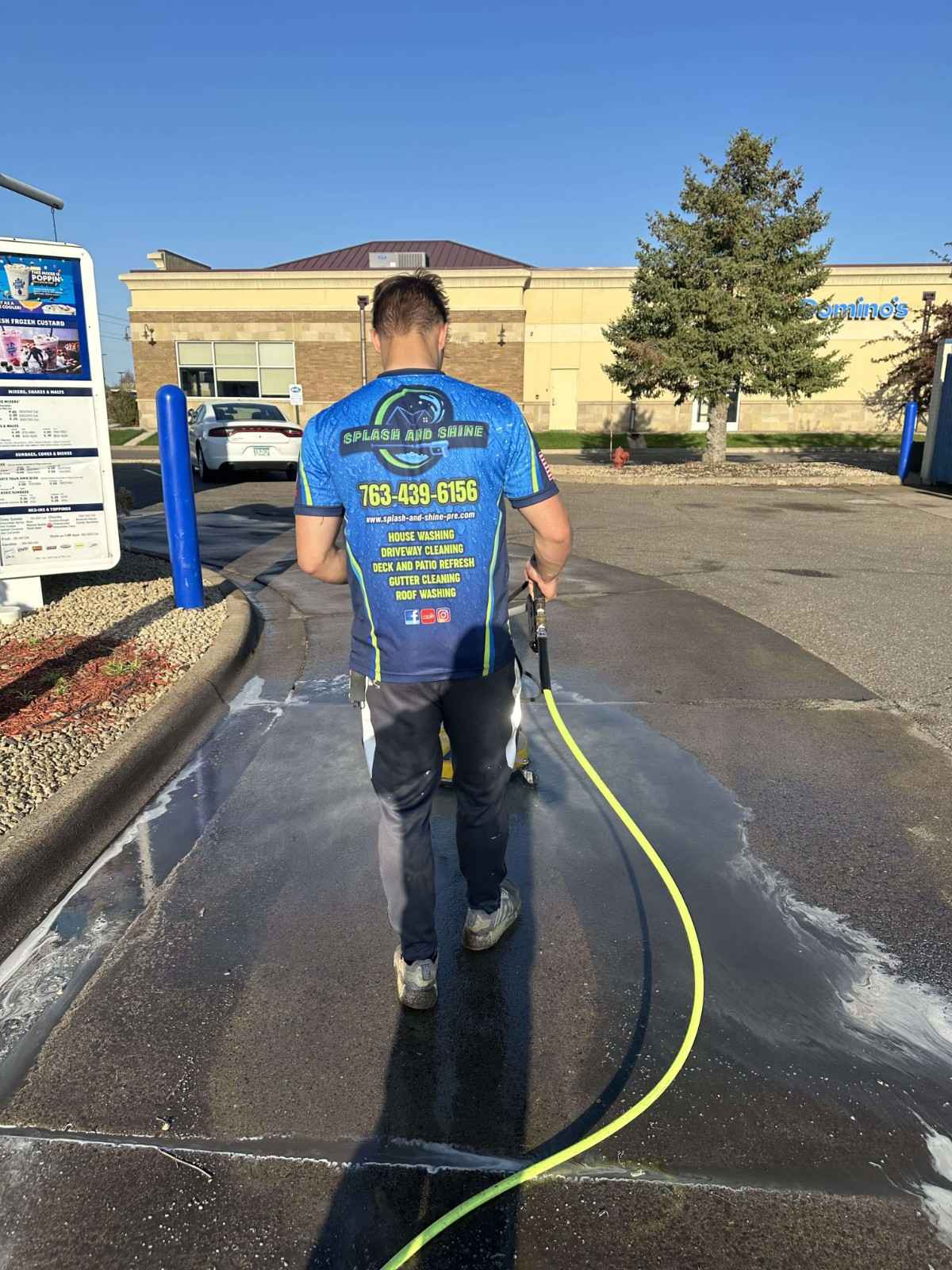 Splash & Shine technician cleaning a commercial driveway area with surface cleaner in Cambridge Minnesota