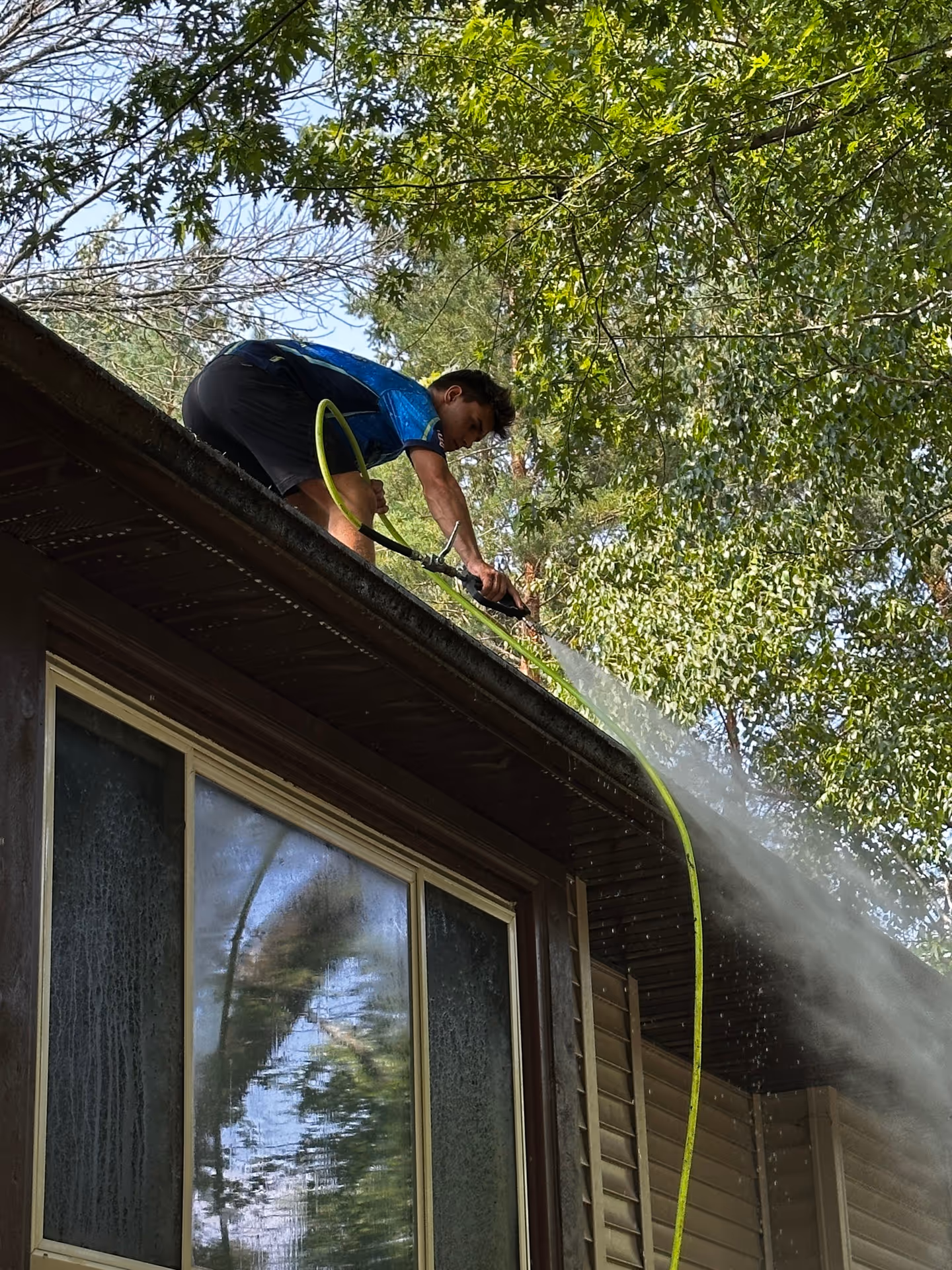 Splash & Shine technician cleaning gutters and flushing downspouts