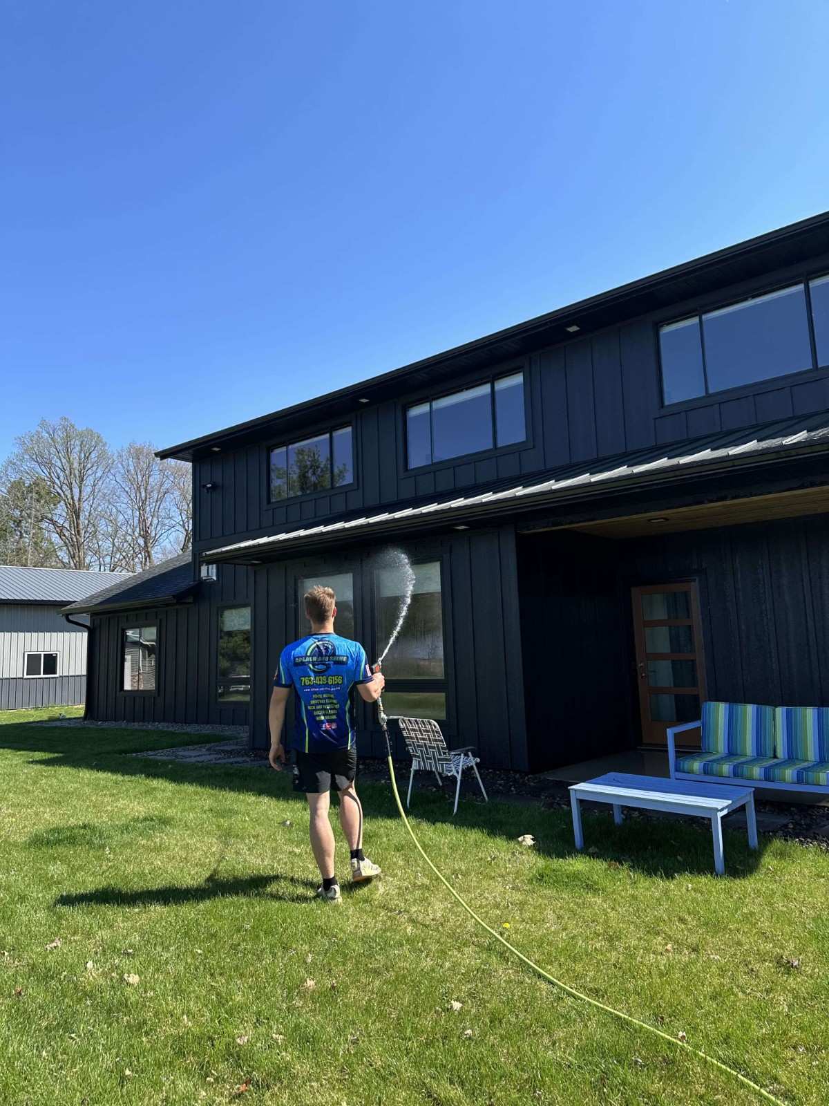 Splash & Shine professional soft washing the exterior of a modern black home in Cambridge Minnesota