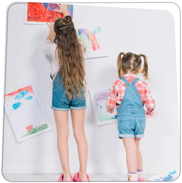 Két gyermek, falra ragasztja a saját rajzait, játékból kiállítást rendeznek