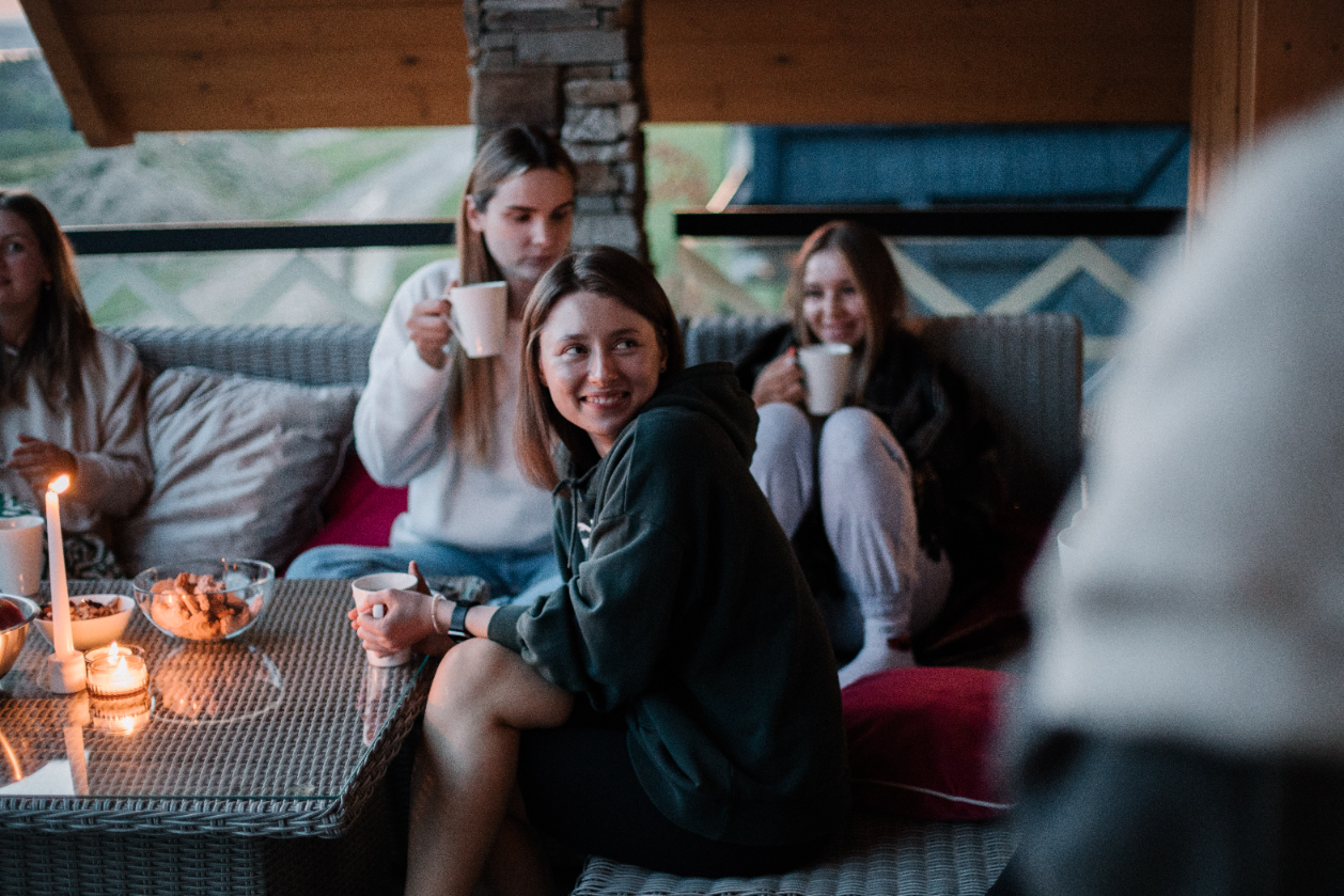 An image of three smiling women sitting with the mugs. Image is in color. They're looking on each other 