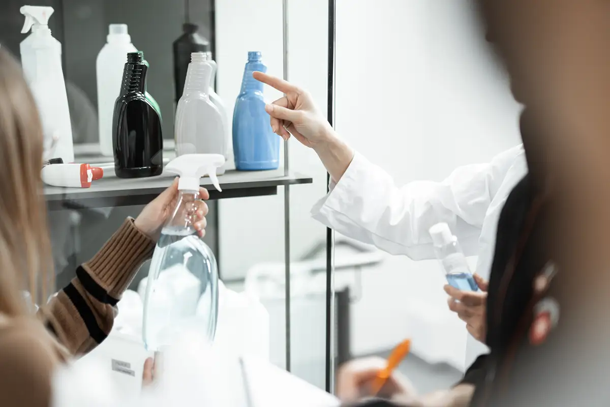 Menschen halten eine Sprühflasche in der Hand und deuten auf eine Vitrine voller Gebinde