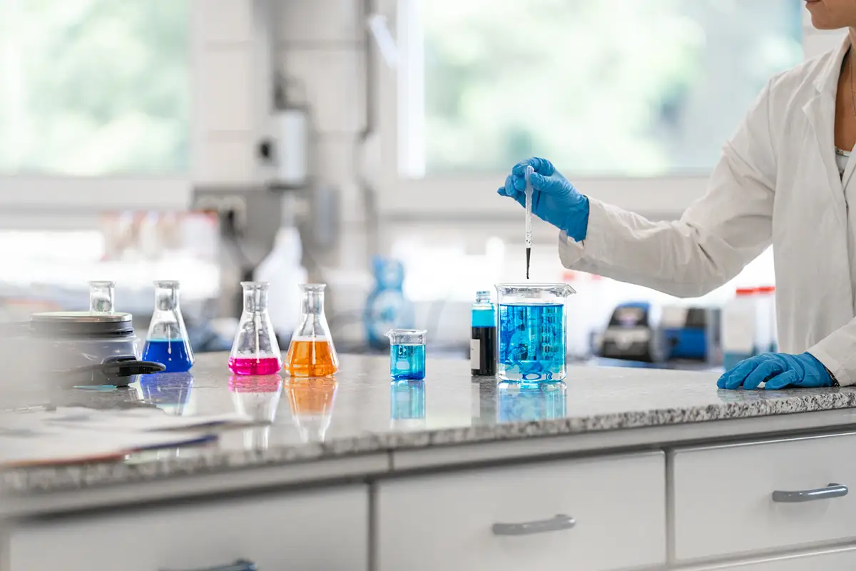 mit einer Pipette wird eine blaue Flüssigkeit in ein Glas gemacht