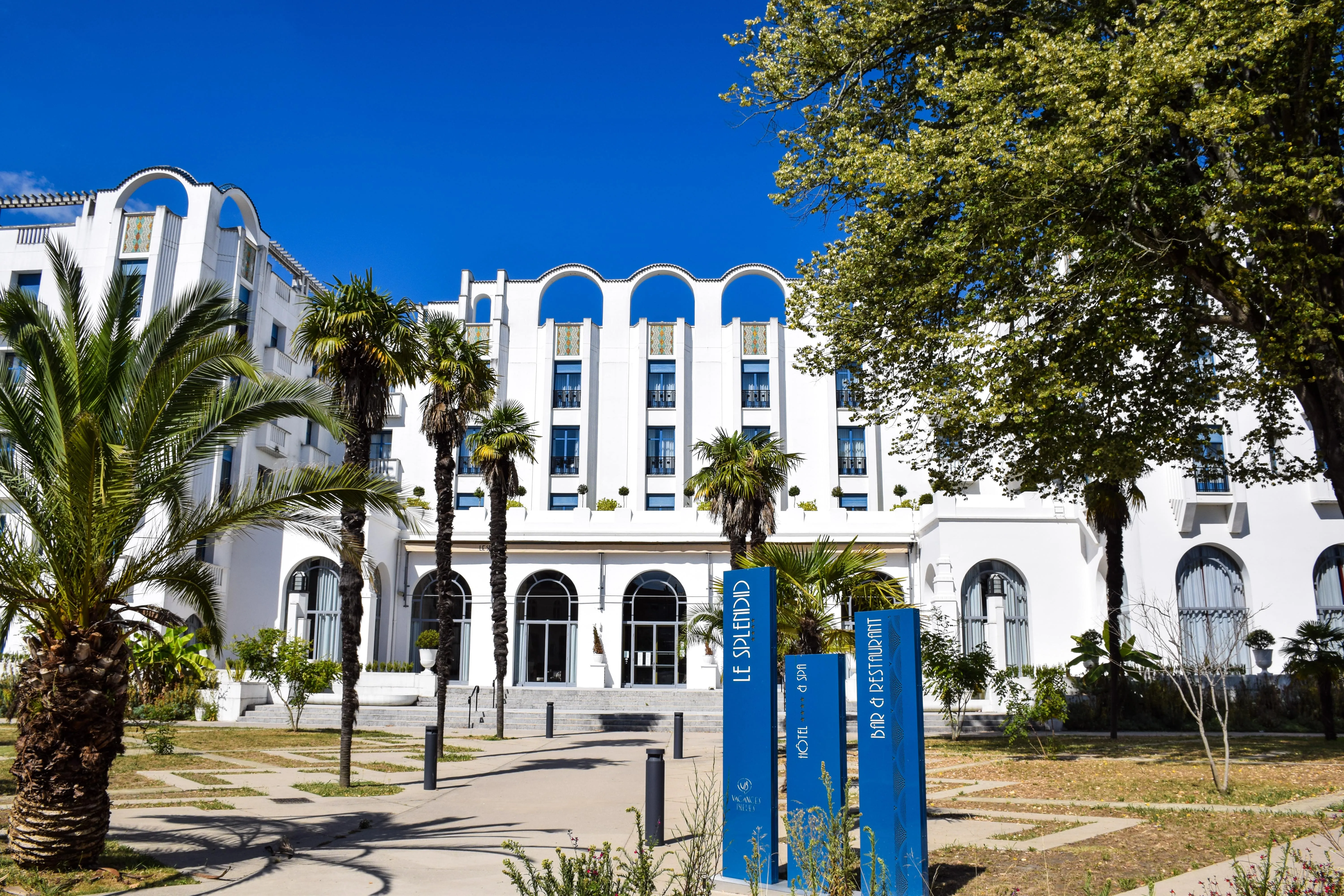 Vue extérieure d’un bâtiment blanc avec palmiers à Dax
