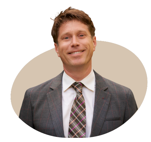 A professional portrait of the director of a private medical insurance brokerage, dressed in a business suit, standing in a modern office setting with a confident and approachable expression.