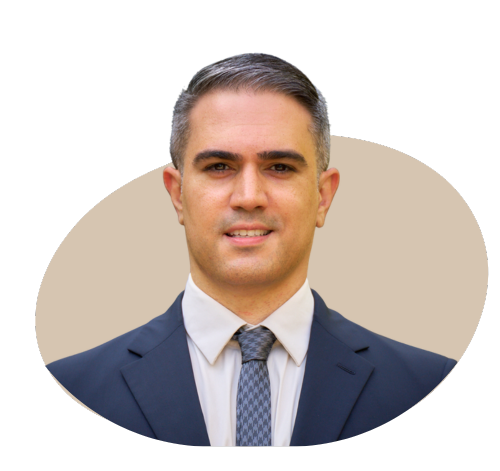 A professional portrait of the director of a private medical insurance brokerage, dressed in a business suit, standing in a modern office setting with a confident and approachable expression.