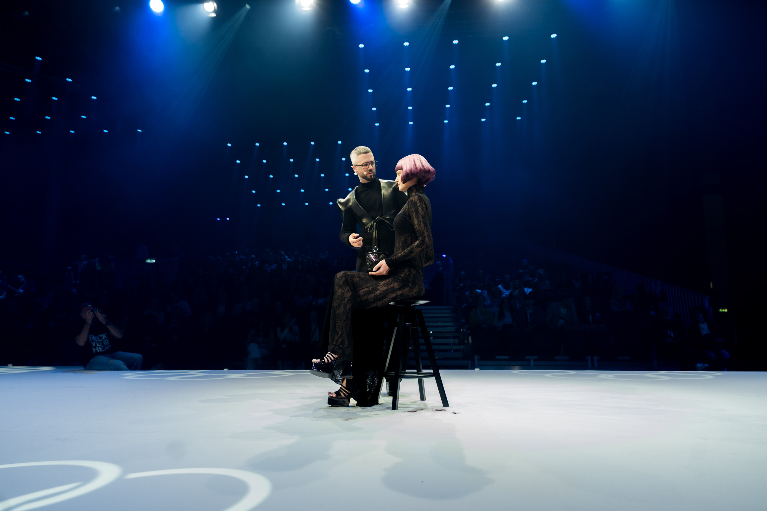 Stylist presenting a pink bob cut on stage at the Goldwell hair show