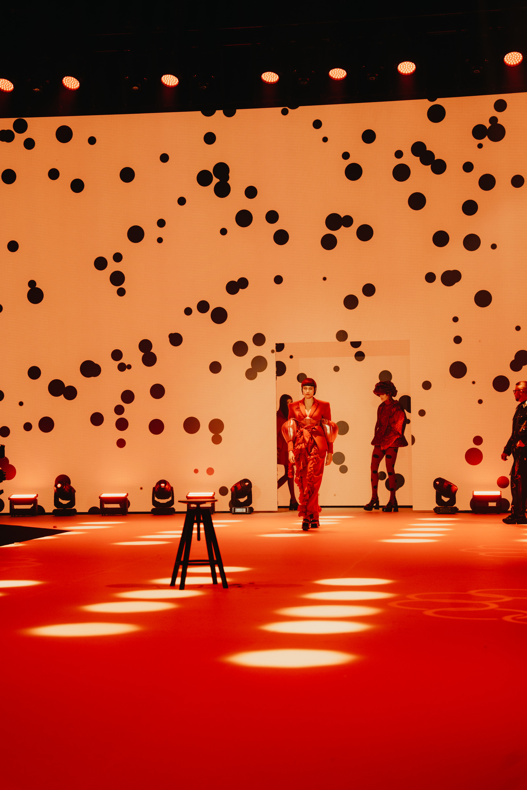 Model in red on the runway against a polka-dot backdrop, Goldwell hair show