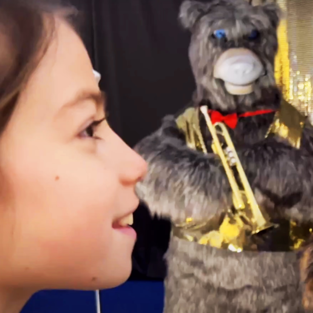 Little girl interacts with Menart animated robotic character equipped with blue LED eyes, demonstrating an immersive multimedia experience for children's entertainment.