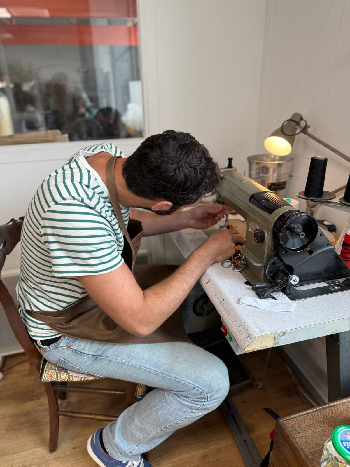 Homme assis travaillant sur une machine à coudre industrielle dans un atelier.