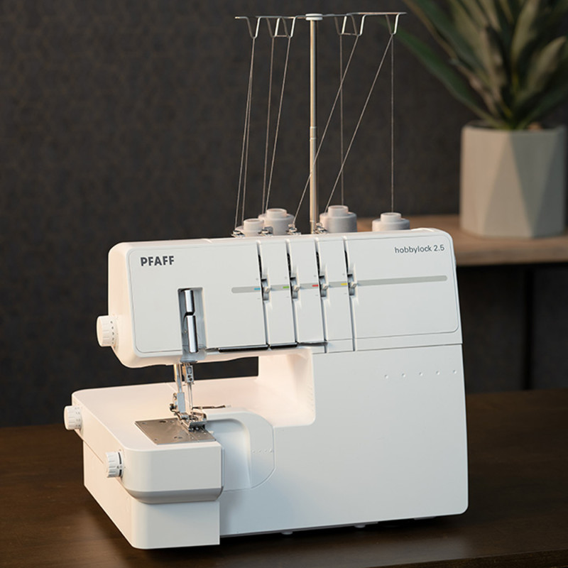 Machine à coudre surjeteuse Pfaff hobbylock 2.5 blanche posée sur une table en bois.