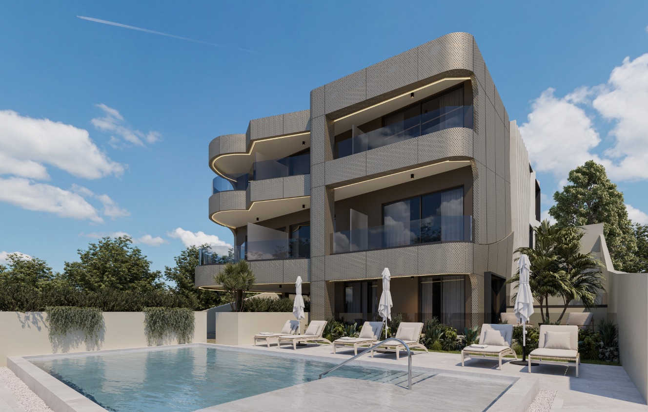 Edifício residencial contemporâneo de três andares com varandas curvas e revestimento metálico perfurado, em frente a uma piscina com espreguiçadeiras e zonas de lazer ao ar livre.