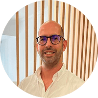 Fotografia de Miguel Henriques arquiteto e gerente da MHArquiteto. Homem careca de óculos e sorridente.